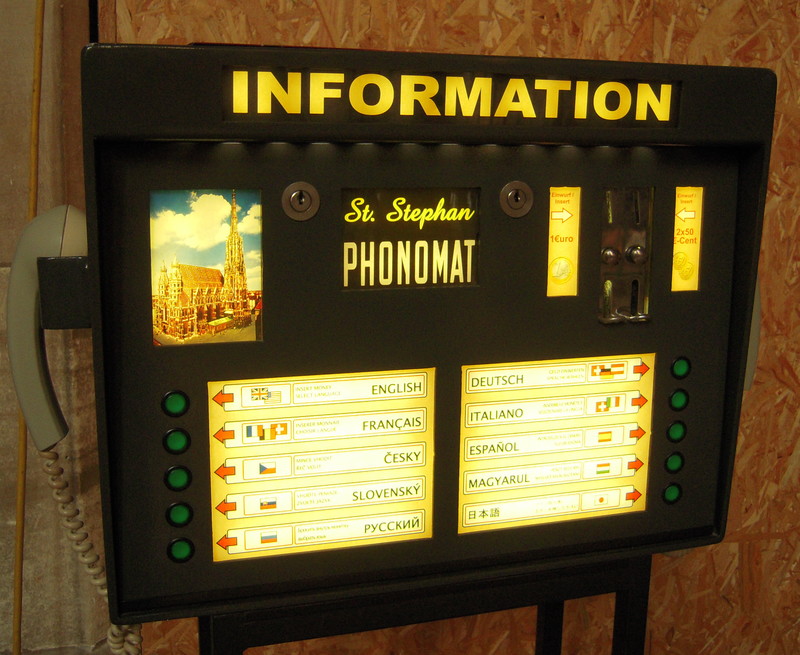 A box labeled INFORMATION and St Stephan PHONOMAT, with a telephone receiver
	(lacking mouthpiece) hanging from either side, slots for accepting Euro coins, and buttons for selecting English,
	French, Czech, Slovak, Russian, German, Italian, Hungarian, or Japanese languages.